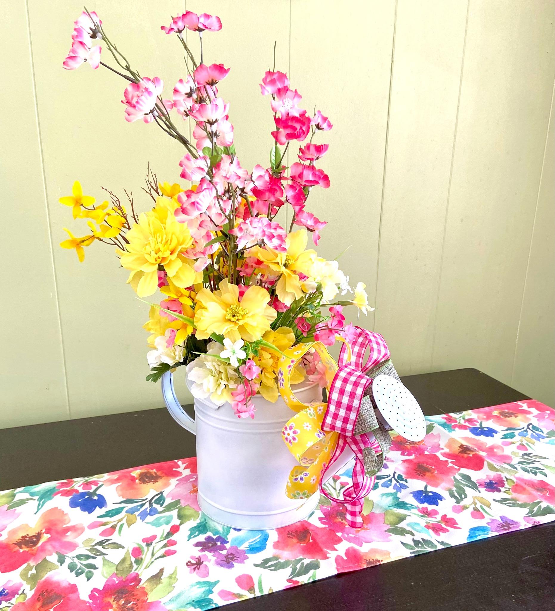 Pink blossom branches and yellow lilies in a white pitcher with a pink gingham bow
